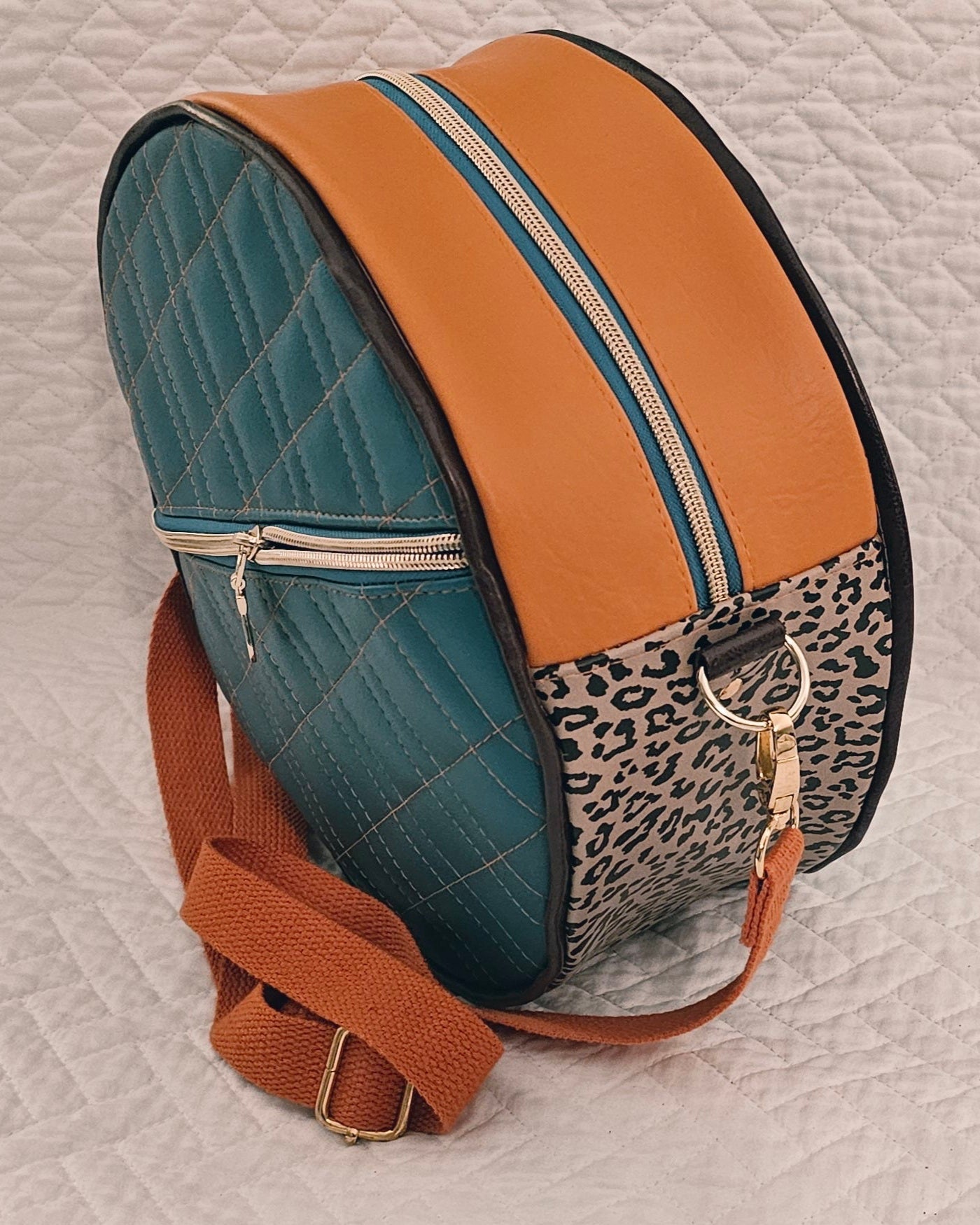 Multicolored round purse with leopard print accent on a textured surface.