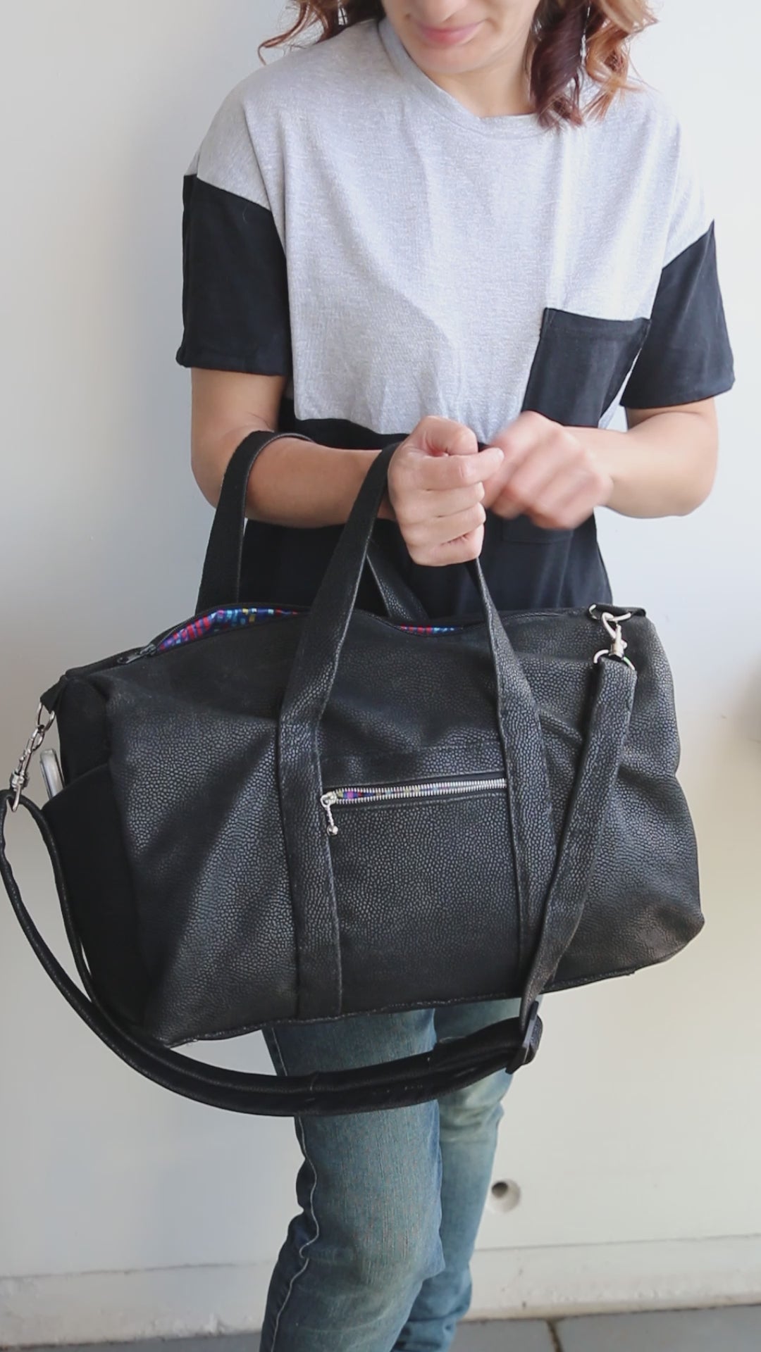 Handmade duffle bag in waterproof black canvas, showcasing its zipper exterior pocket, adjustable straps, and size.