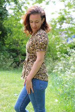 Cheetah print woven wrap top with short puff sleeve on a female model. Easy sewing pattern.