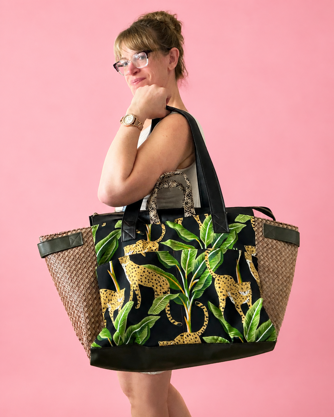 Woman holding a large tote bag with leopard print design against a pink background