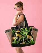 Woman holding a large tote bag with leopard print design against a pink background