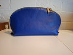 Blue cosmetic bag with a gold zipper on a white surface.