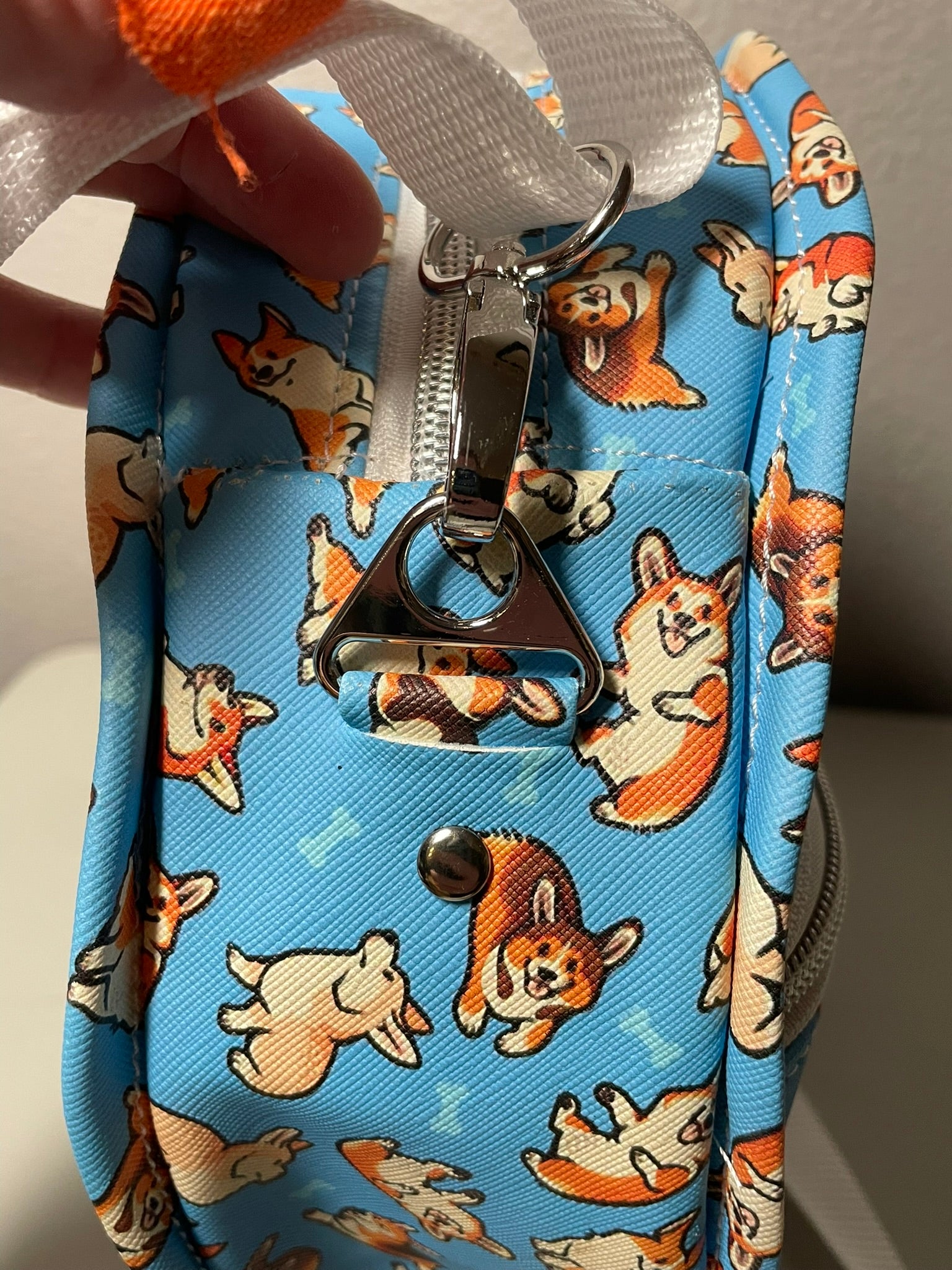 Blue DIY pouch with corgi pattern and zipper, held by a hand.