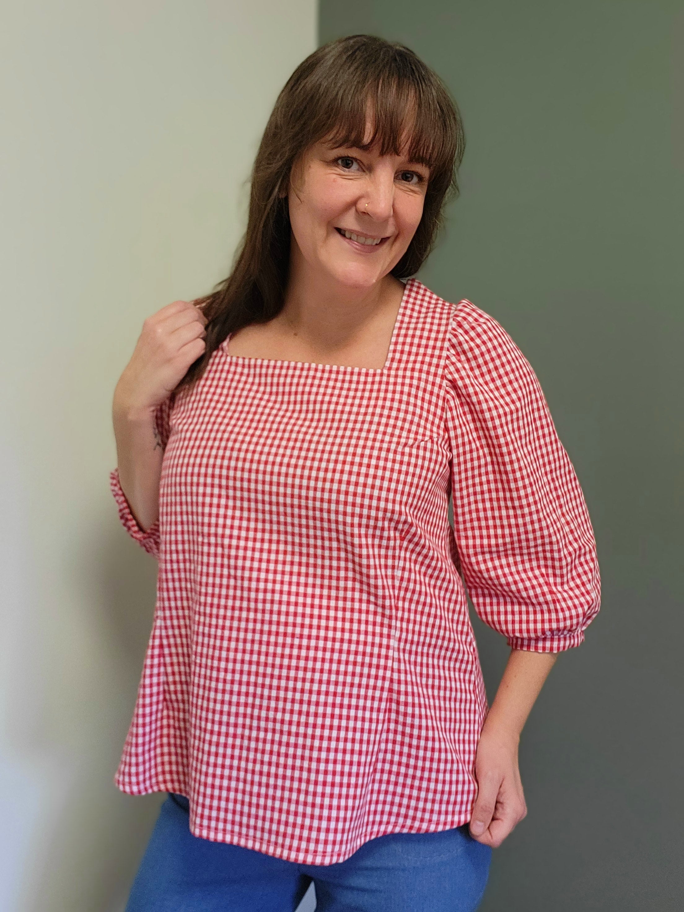 Woman wearing a red and white checkered handmade Zara blouse against a plain background