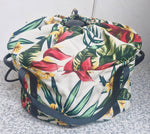 Tropical floral patterned slow cooker bag with a strap on a textured surface. Insulated and quilted to keep your food warm. 