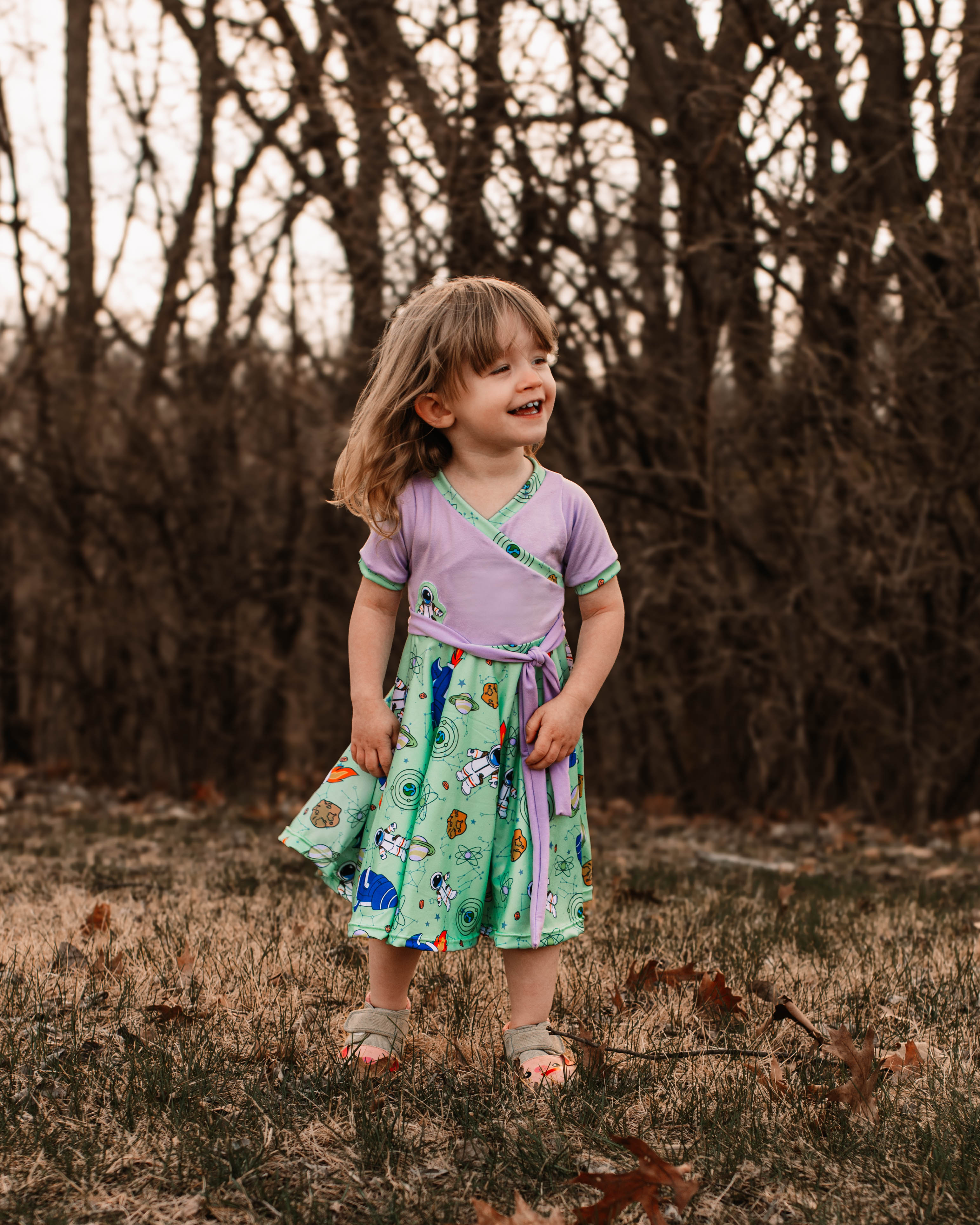 Cute Space fabric dress with faux wrap bodice and short sleeves. Circle skirt for twirling. Toddler to teen sewing pattern.