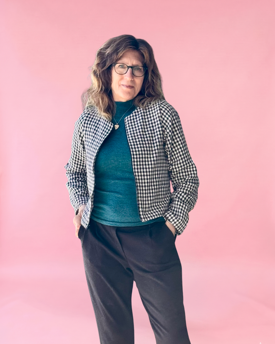 Person wearing a checkered jacket over a green shirt with a pink background