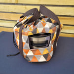 Geometric patterned crock pot bag with a strap on a wooden surface. This carrier was made using the warm and cozy slow cooker carrier pattern by Ellie and Mac sewing patterns.
