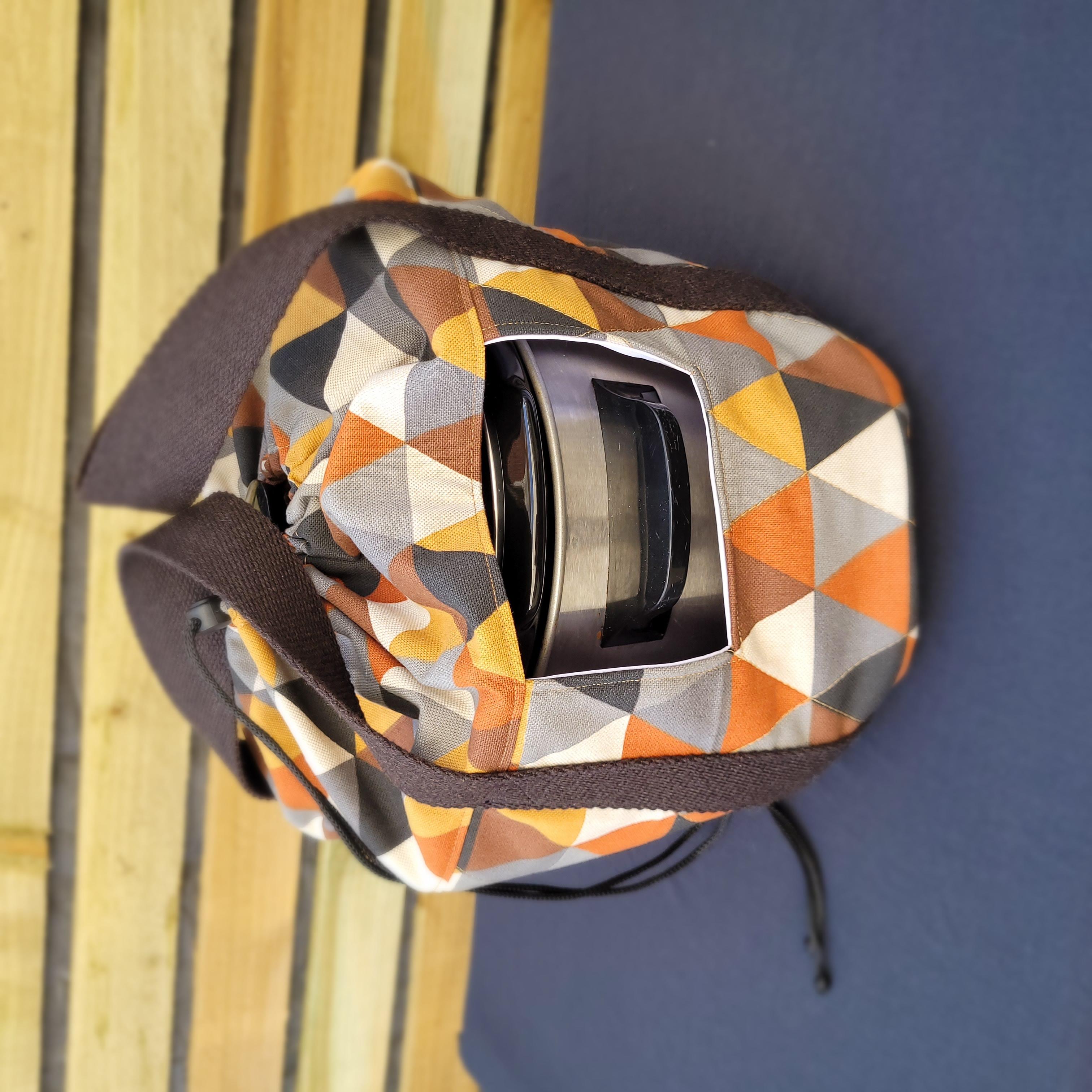 Geometric patterned crock pot bag with a strap on a wooden surface. This carrier was made using the warm and cozy slow cooker carrier pattern by Ellie and Mac sewing patterns.