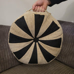 Round cushion with black and beige pattern held by a person against a neutral background. Sprocket quilted pillow pattern by Ellie & Mac sewing patterns.