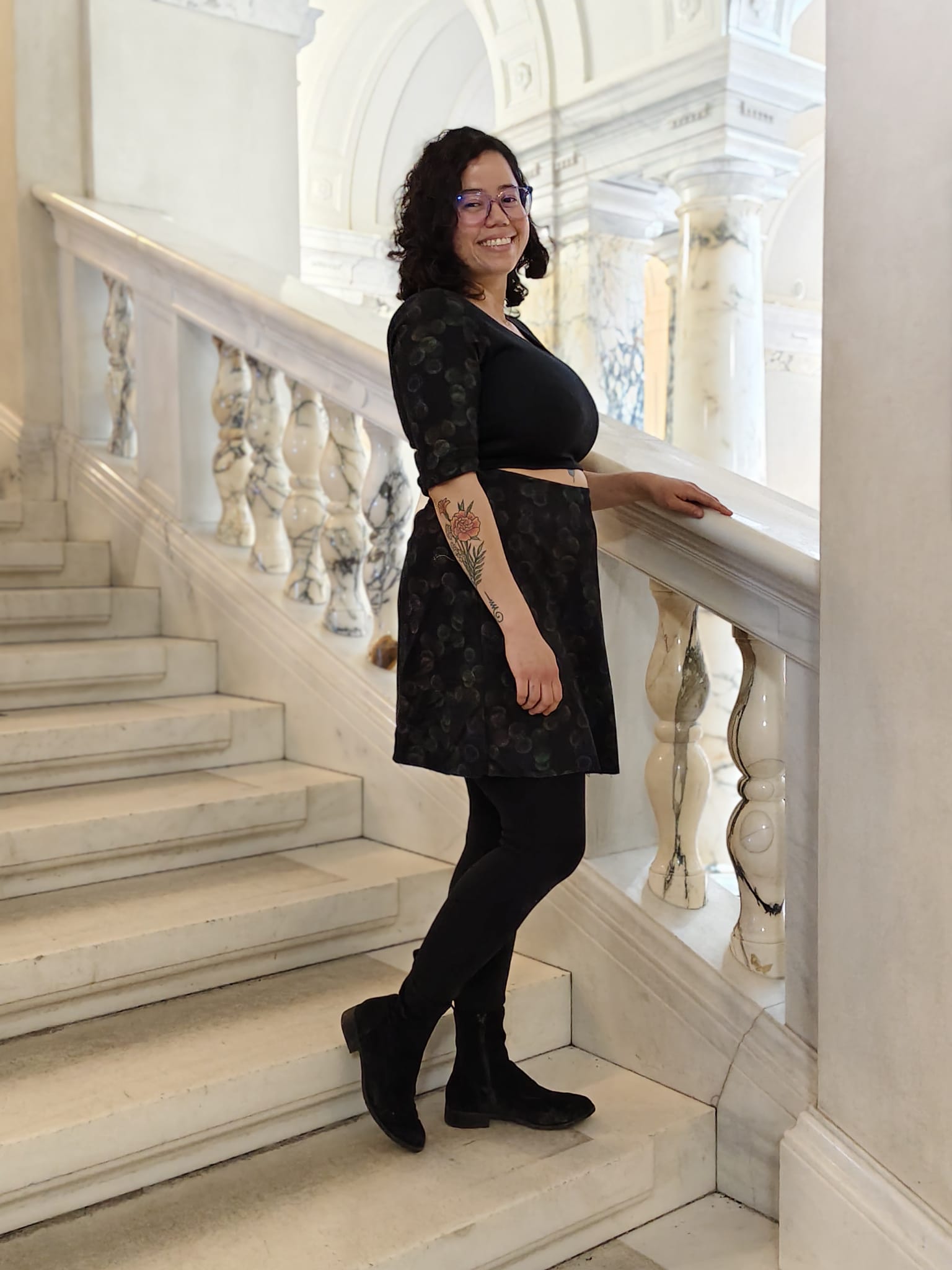 Woman in a black cut-out dress standing on a marble staircase