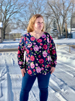 Woman wearing a floral faux wrap sweater and blue jeans standing in a snowy outdoor setting.