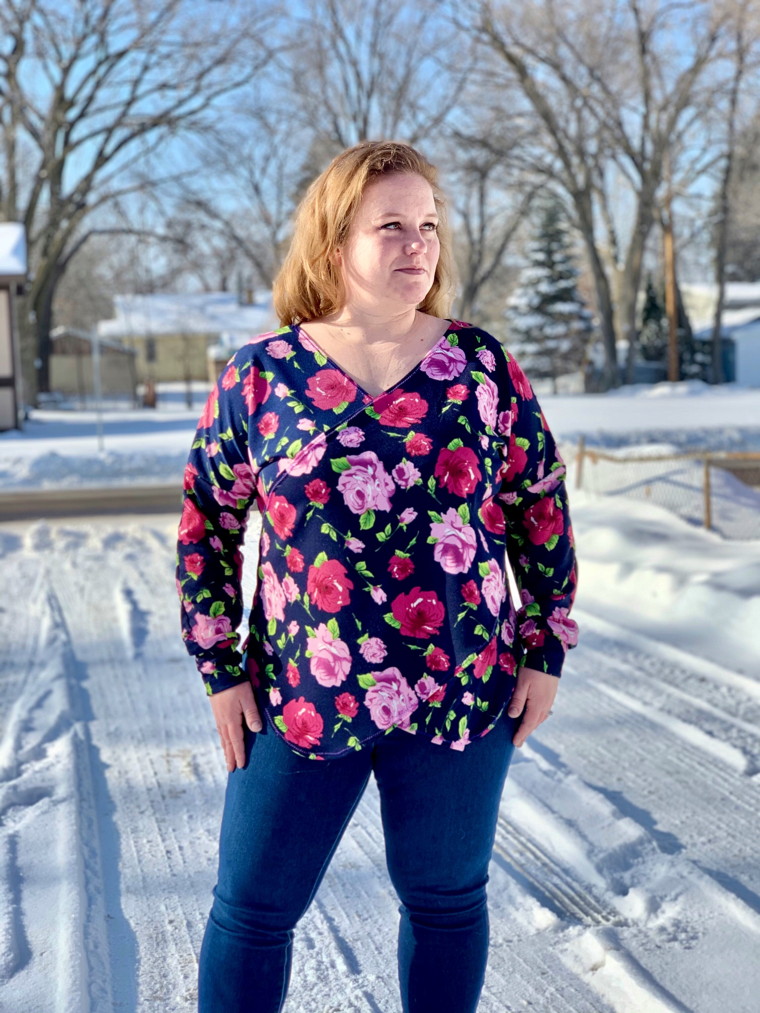 Woman wearing a floral faux wrap sweater and blue jeans standing in a snowy outdoor setting.