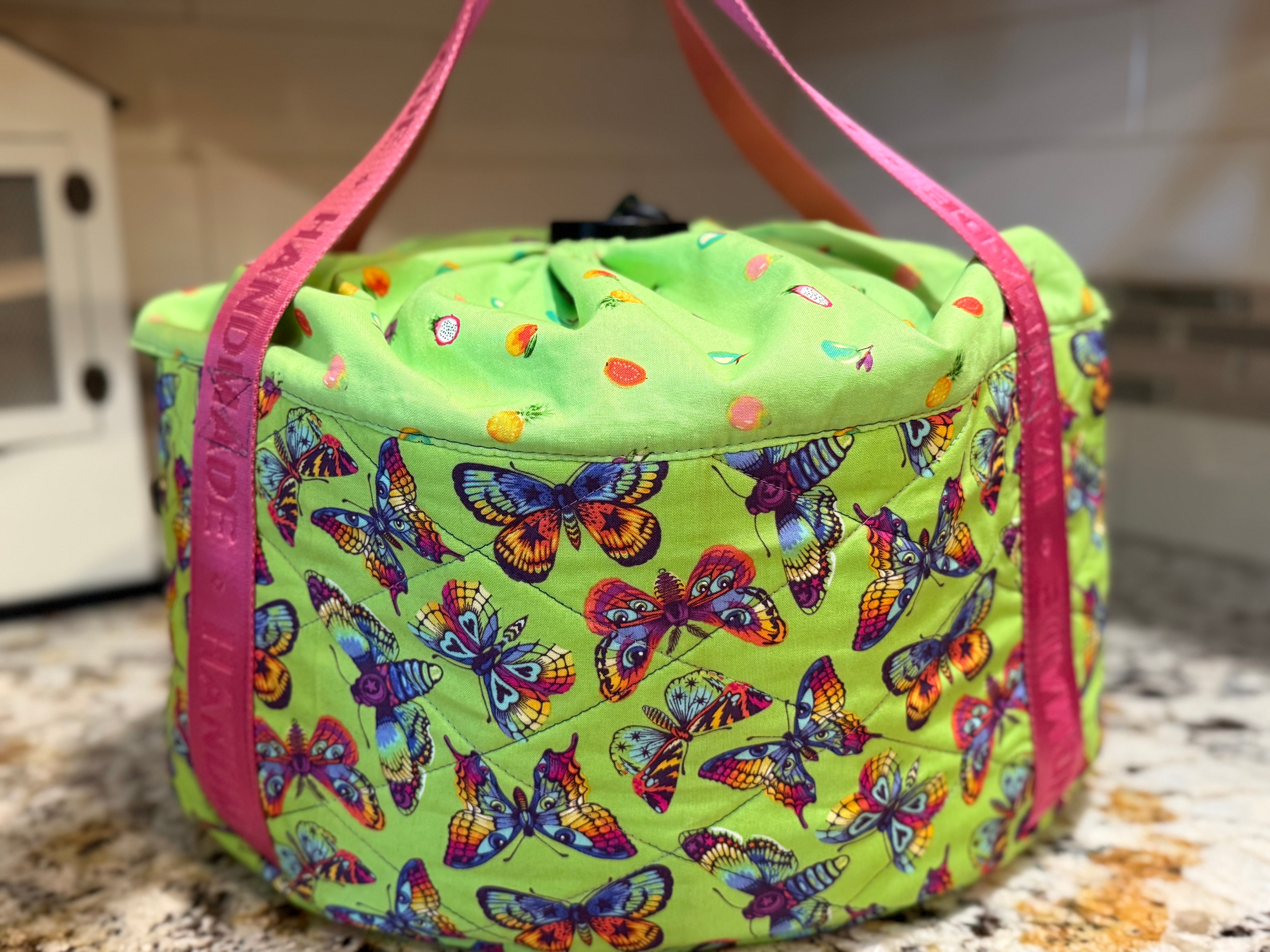 Lime green slow cooker carrier bag with butterfly pattern and pink handles on a kitchen counter. DIY sewing.