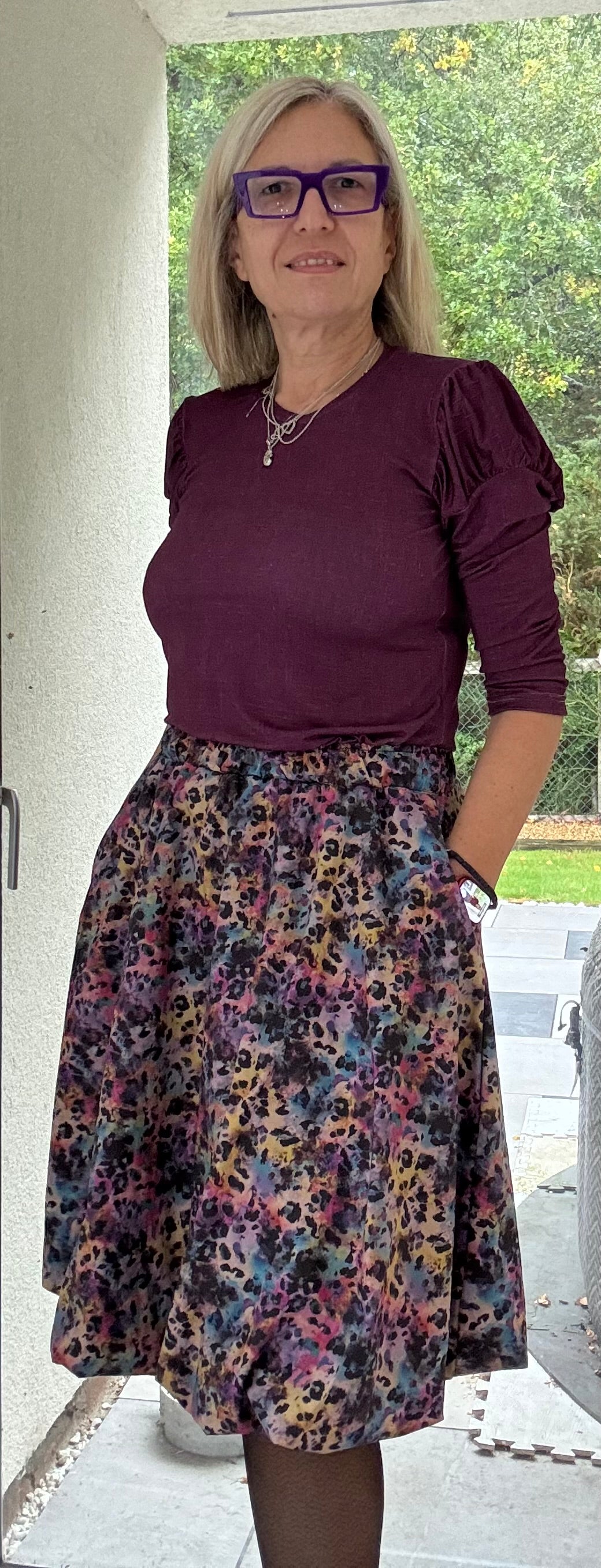 Woman wearing a maroon top and floral bubble skirt standing outdoors. This entire outfit was made using Ellie and Mac's Beginner Friendly sewing patterns. 