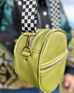 Green round bag with a checkered strap worn by a person