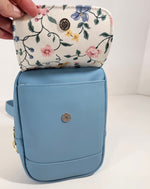 Blue pouch with floral patterned flap held by a hand on a white background