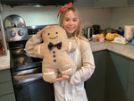 Person holding a gingerbread man plush toy in a kitchen setting