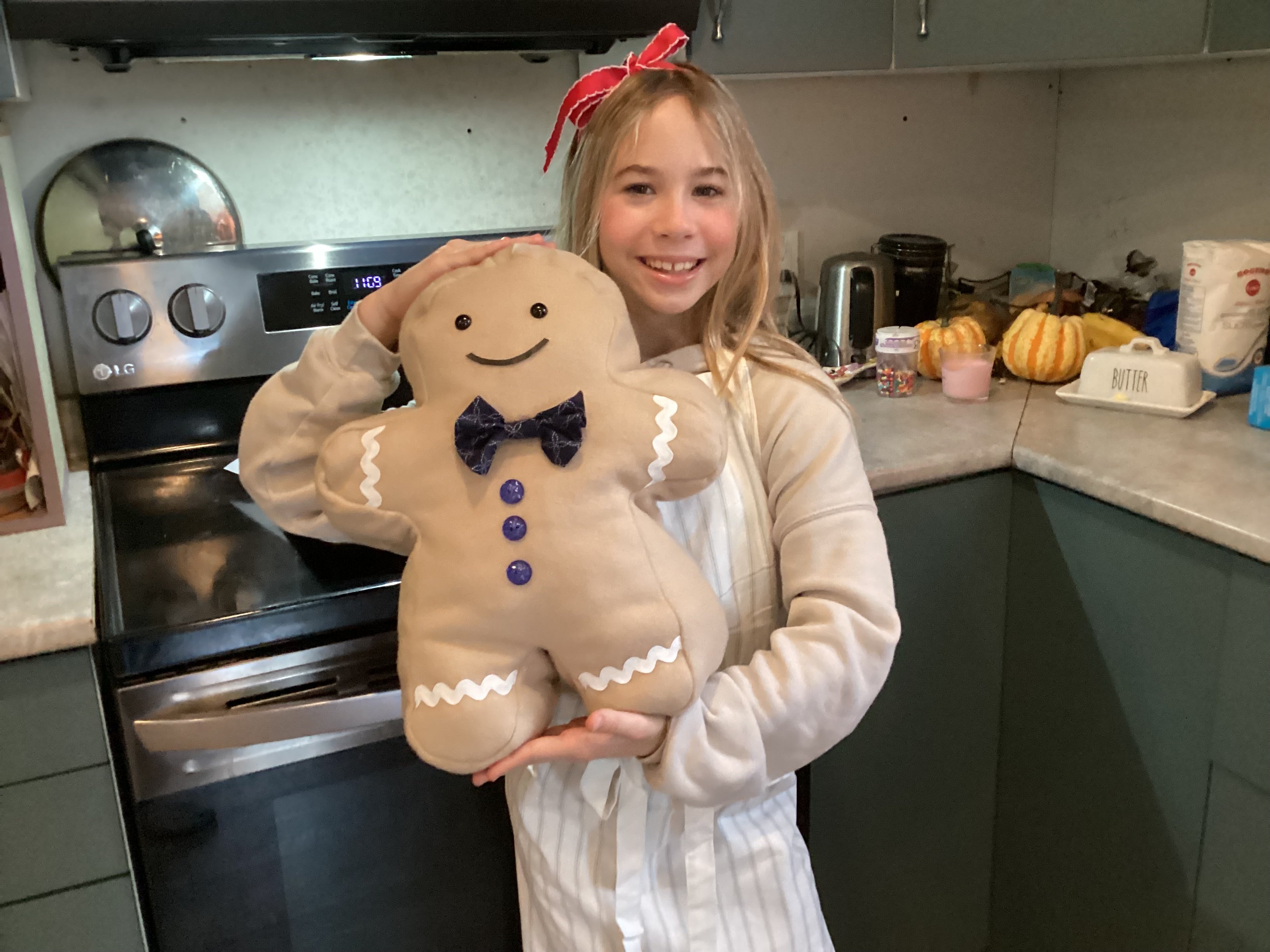 Person holding a gingerbread man plush toy in a kitchen setting