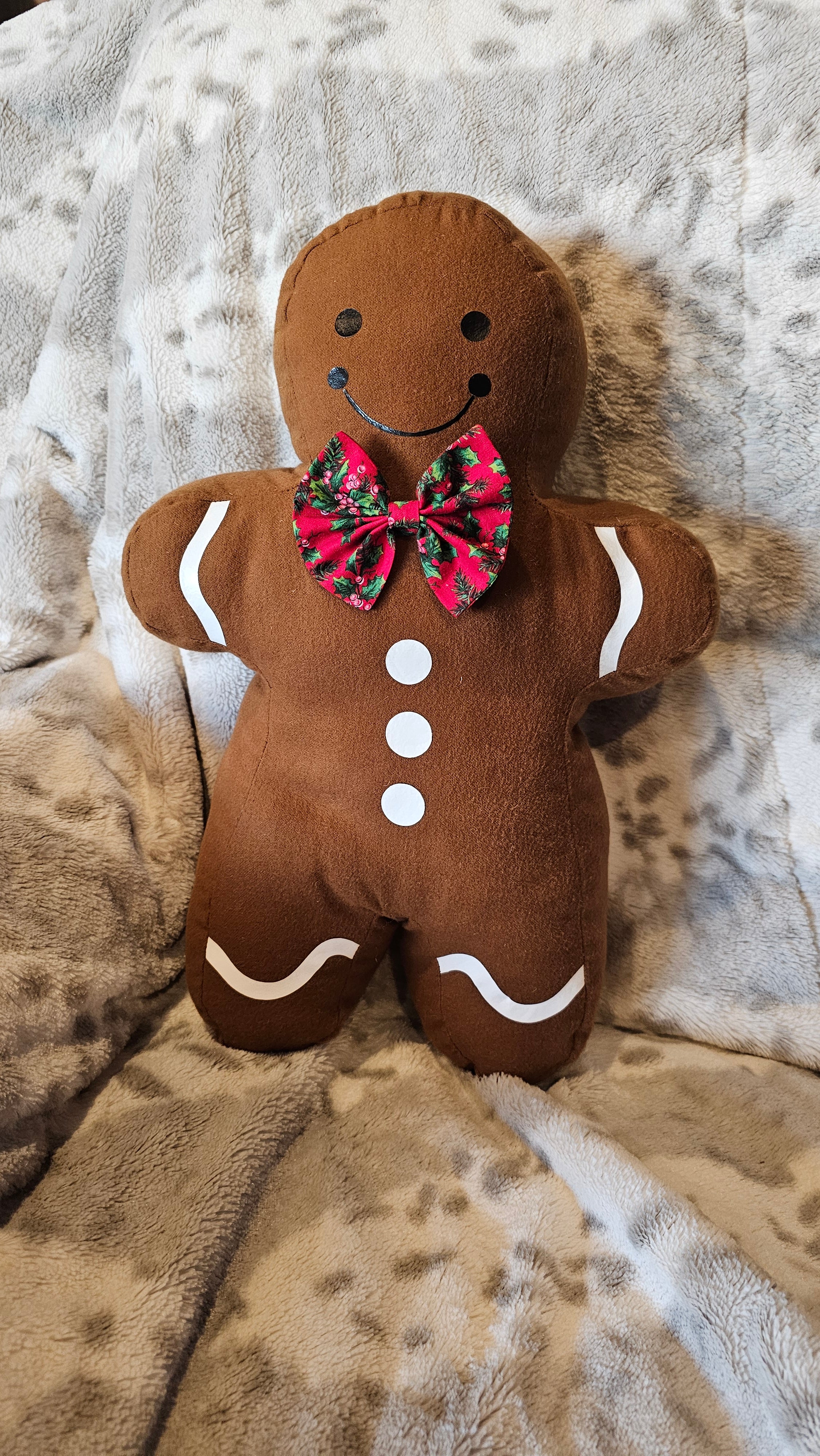 Gingerbread man plush toy with a bow tie on a textured surface