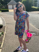 Young girl in a colorful dress with a toy pail on a driveway