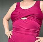 Person wearing a pink sleeveless swimsuit against a gray background