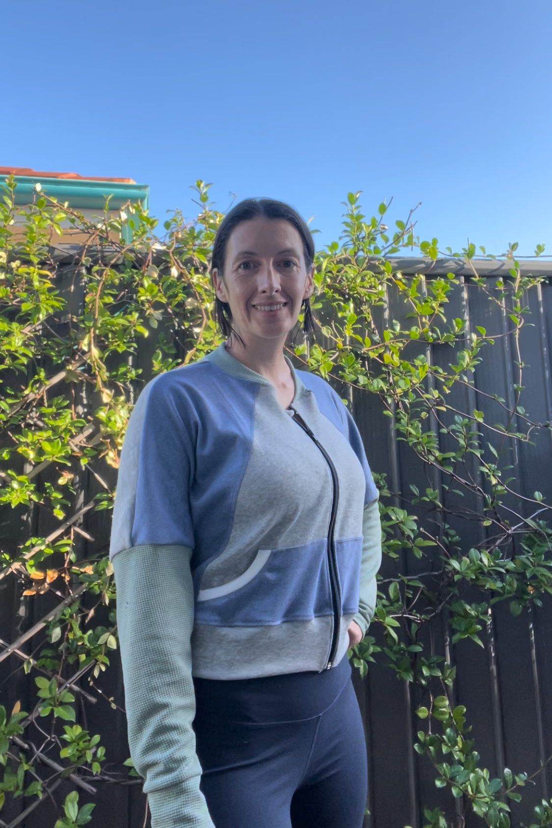 Woman wearing a zip up athletic jacket with raglan dolman sleeves, kangaroo pocket, and curved waistband. Sewing pattern for jackets by Ellie and Mac sewing patterns. 