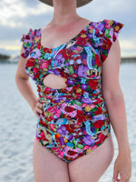 Person wearing a colorful patterned swimsuit on a beach.