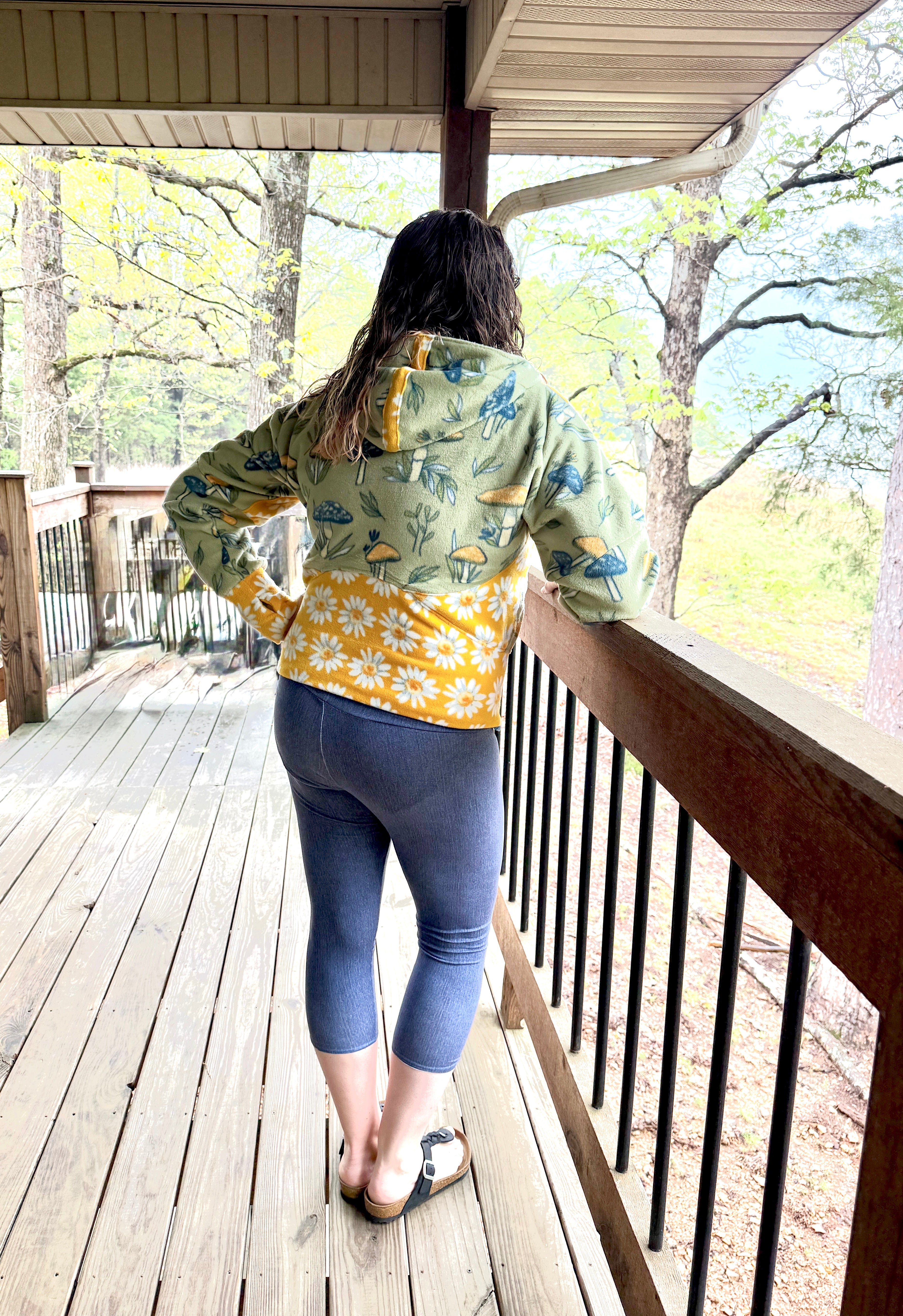 Woman on a deck modeling a bright color-block athletic hooded jacket with zip closure, kangaroo pocket detail, and cuffs. Easy pdf sewing pattern.