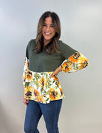 Woman wearing a green peasant top with floral bishop sleeves against a plain background. Easy sewing pattern for fall.