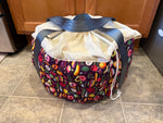 Colorful slow cooker insulated carrier bag with drawstring top on a tiled floor. Easy craft sewing patterns for the home. Makes great holiday and housewarming gifts!