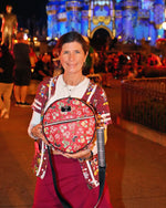 Person holding a backpack with Cinderella Castle in the background at night.