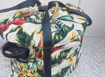 Floral-patterned crock pot insulated bag with black straps on a textured surface.