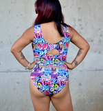 Person wearing a colorful swimsuit with text design against a concrete wall.