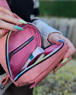 Pink phone bag with a zipper open, showing its interior.