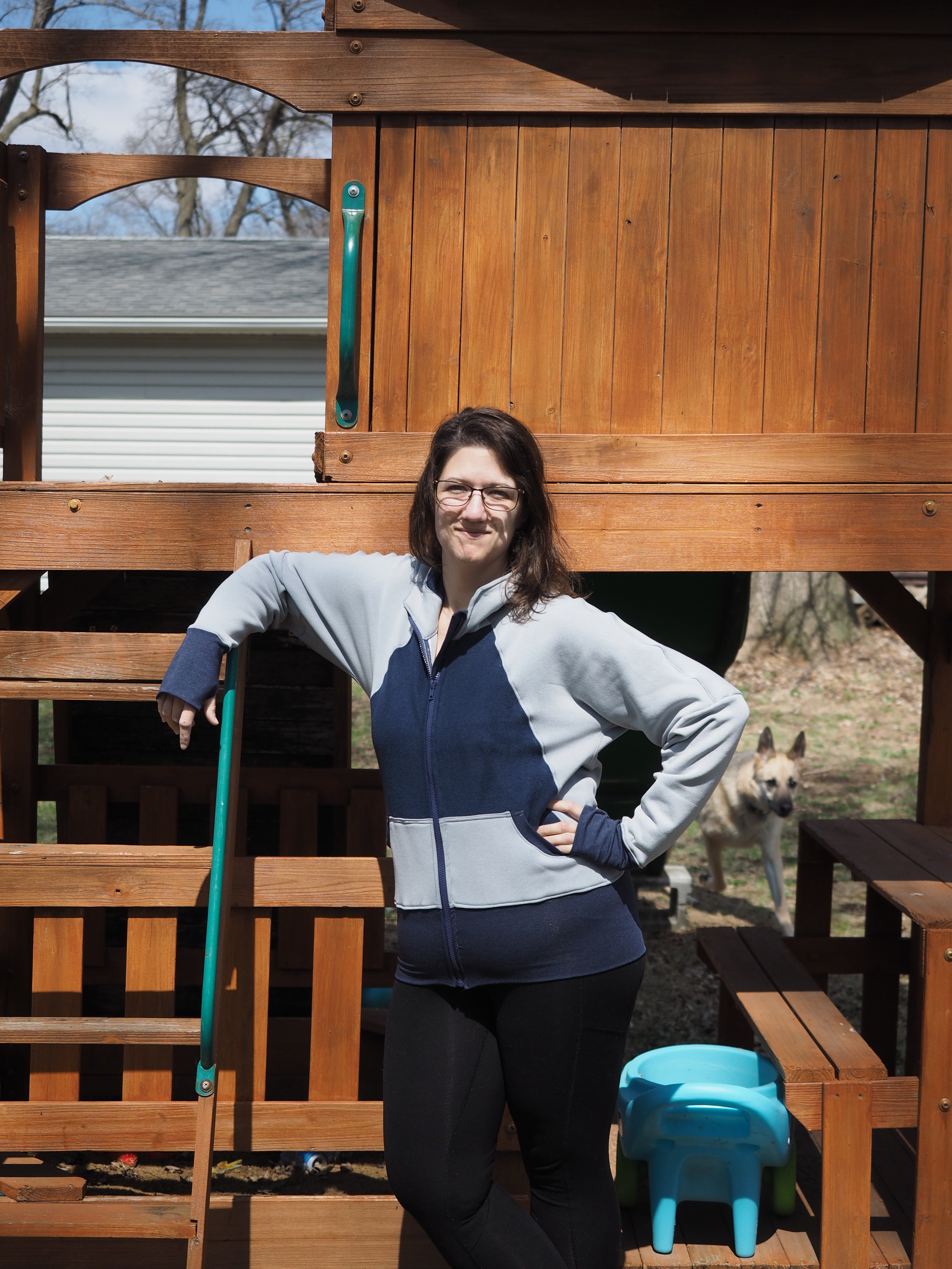 Woman wearing a sweater knit fabric zip-up jacket with raglan dolman sleeves, kangaroo pocket, and curved waistband. Knit fabric sewing pattern - instant download. High Hip Version.