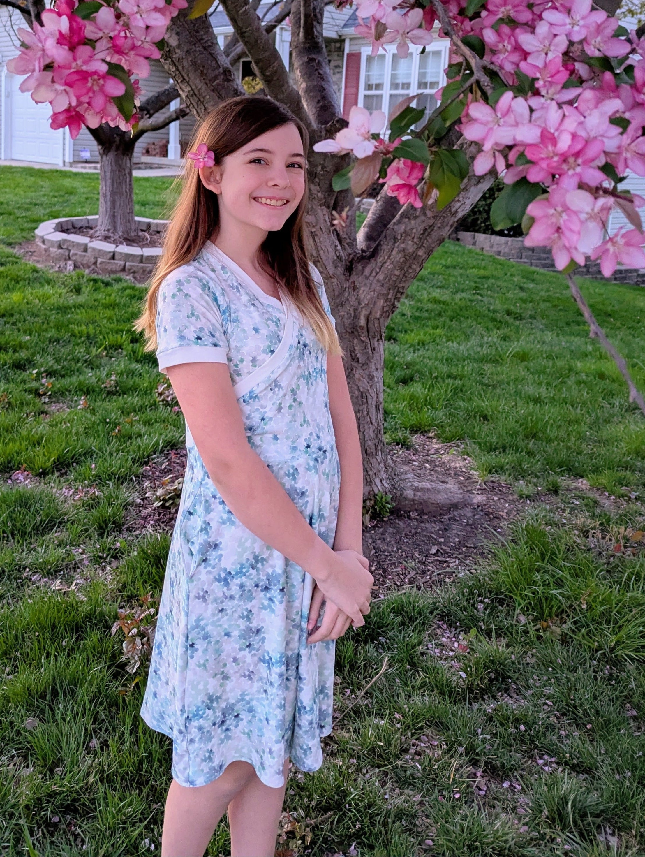 Floral fabric dress with faux wrap bodice and short sleeves. 1/2 Circle skirt with pockets. Toddler to teen sewing pattern.