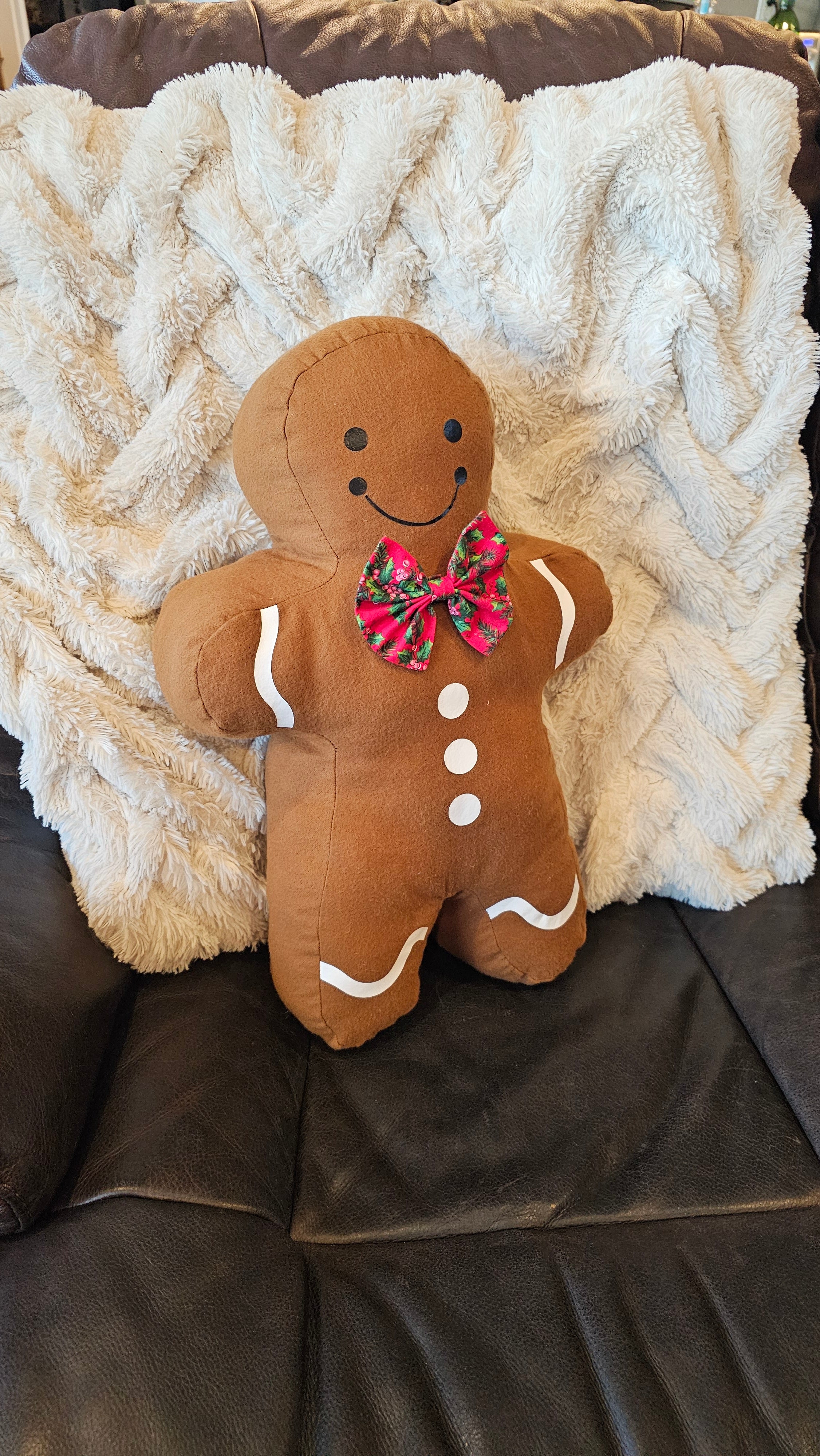 Plush gingerbread man pillow on a textured blanket on a couch.