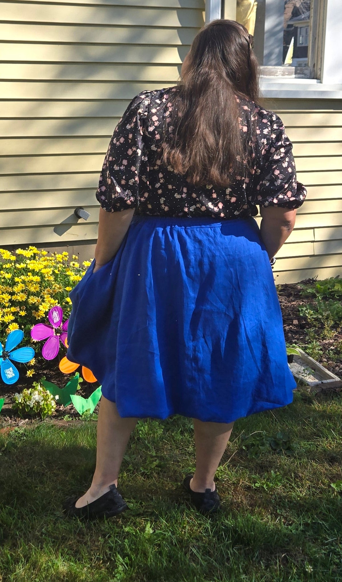 Person standing in front of a house with a garden and flowers. This entire outfit was made using Ellie and Mac's Beginner Friendly sewing patterns. 