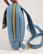 Blue handbag with gold zipper on a light gray background
