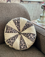 Round pillow with leopard print and beige fabric on a brown couch. DIY Home decor sewing projects. Accessory sewing pattern.