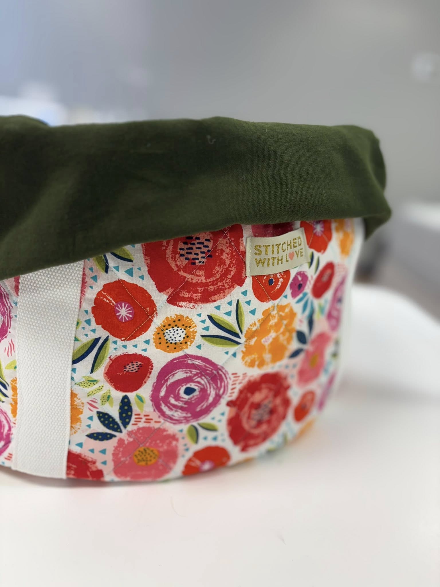Fabric crock pot carrier with floral pattern and green top on a white background