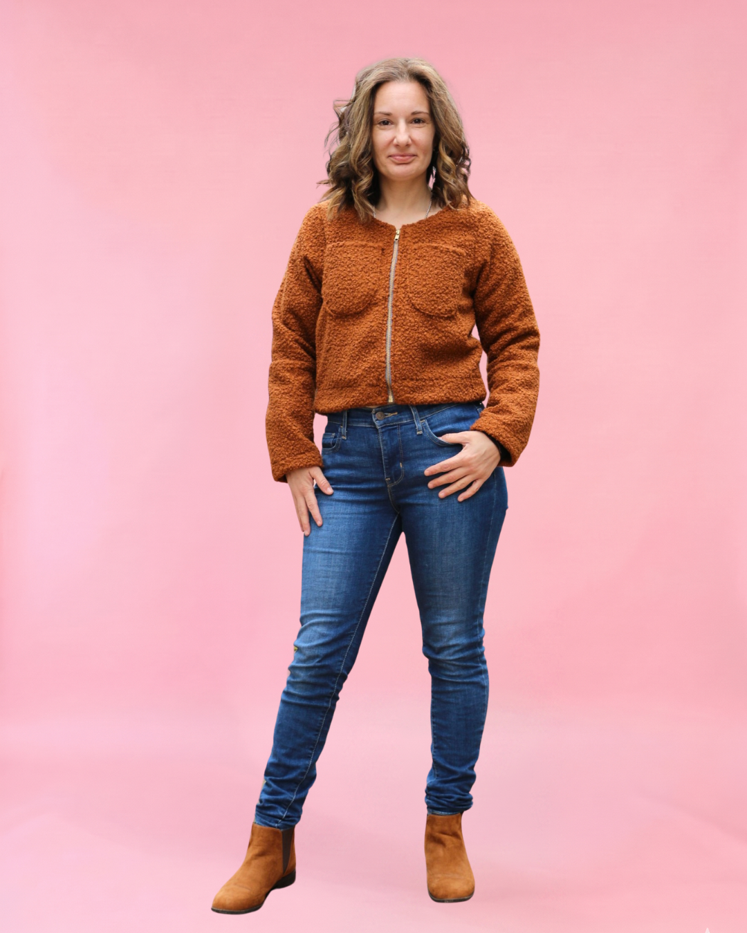 Woman wearing a brown teddy bear fabric jacket and blue jeans against a pink background. PDF sewing patterns for beginners
