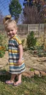 Child wearing a striped dress standing in a garden