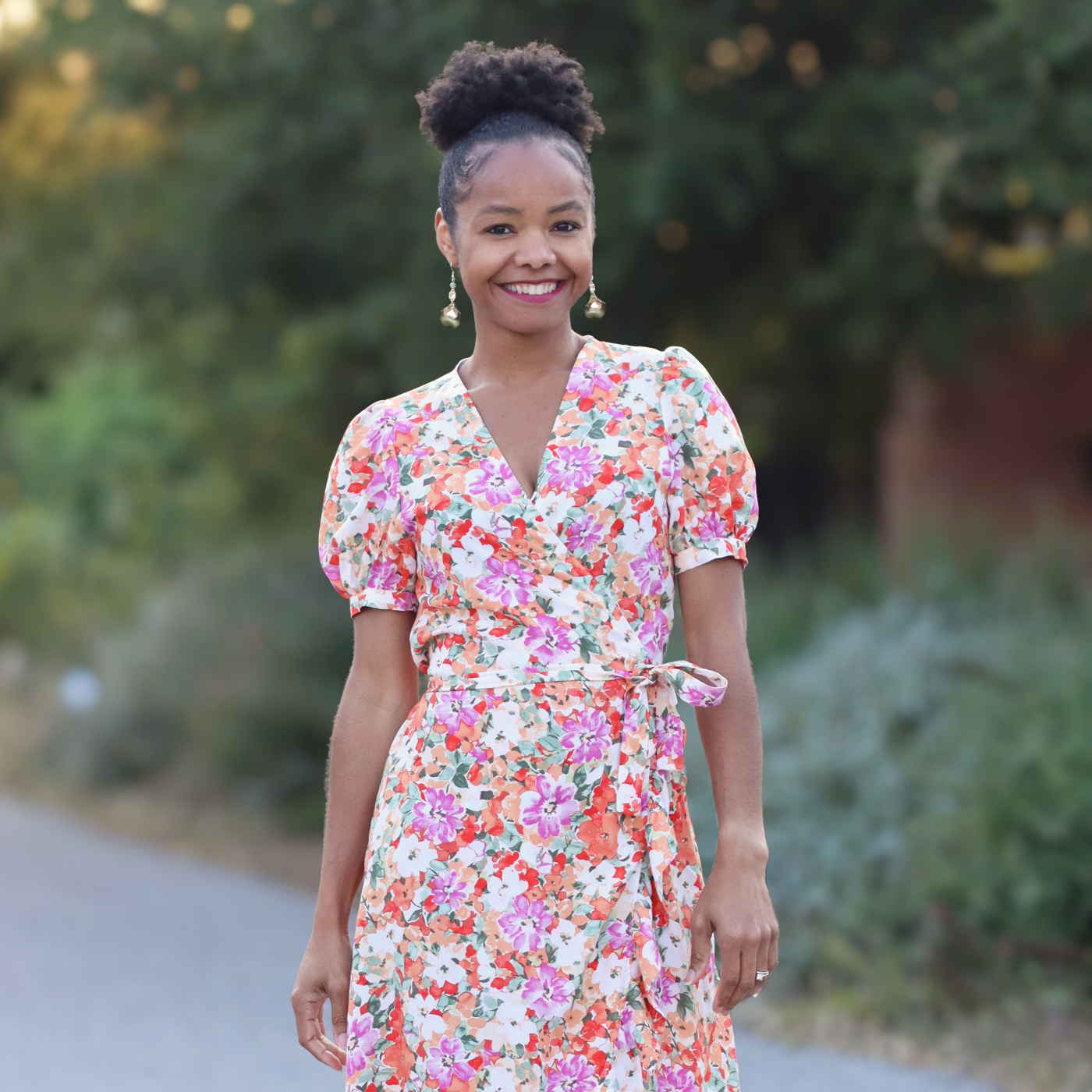 Lakeisha Webb - Pattern Instruction photographer and Writer. She is modeling a floral woven wrap dress with short puff sleeves. 