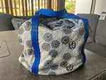 Patterned crock pot bag with blue straps on a table. Quilted sides and insulation make this the perfect slow cooker carrier for all your events! Easy to sew for beginners.