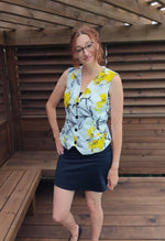 Woman wearing a floral waistcoat and black skirt standing in a wooden structure.