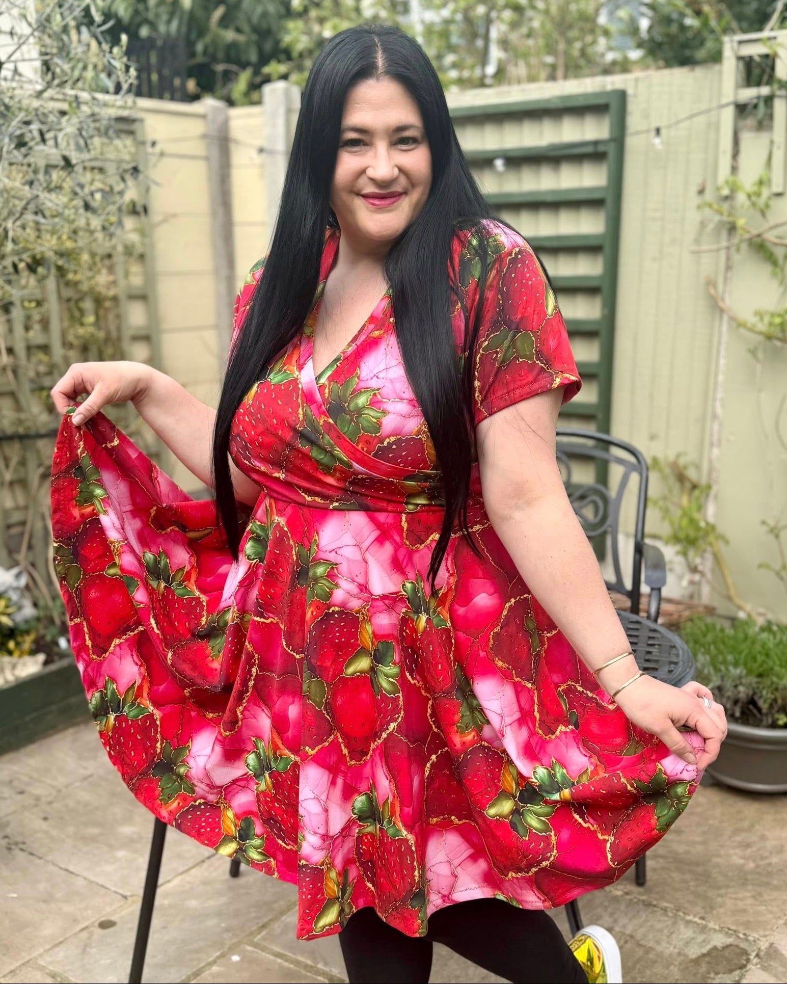 Woman wearing a red strawberry print dress in an outdoor setting. Easy sewing patterns for women.