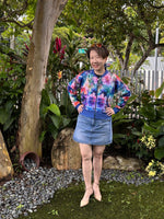 Woman outside modeling a floral and blue athletic bomber jacket with zip closure, kangaroo pocket detail, and cuffs. Easy pdf sewing pattern.
