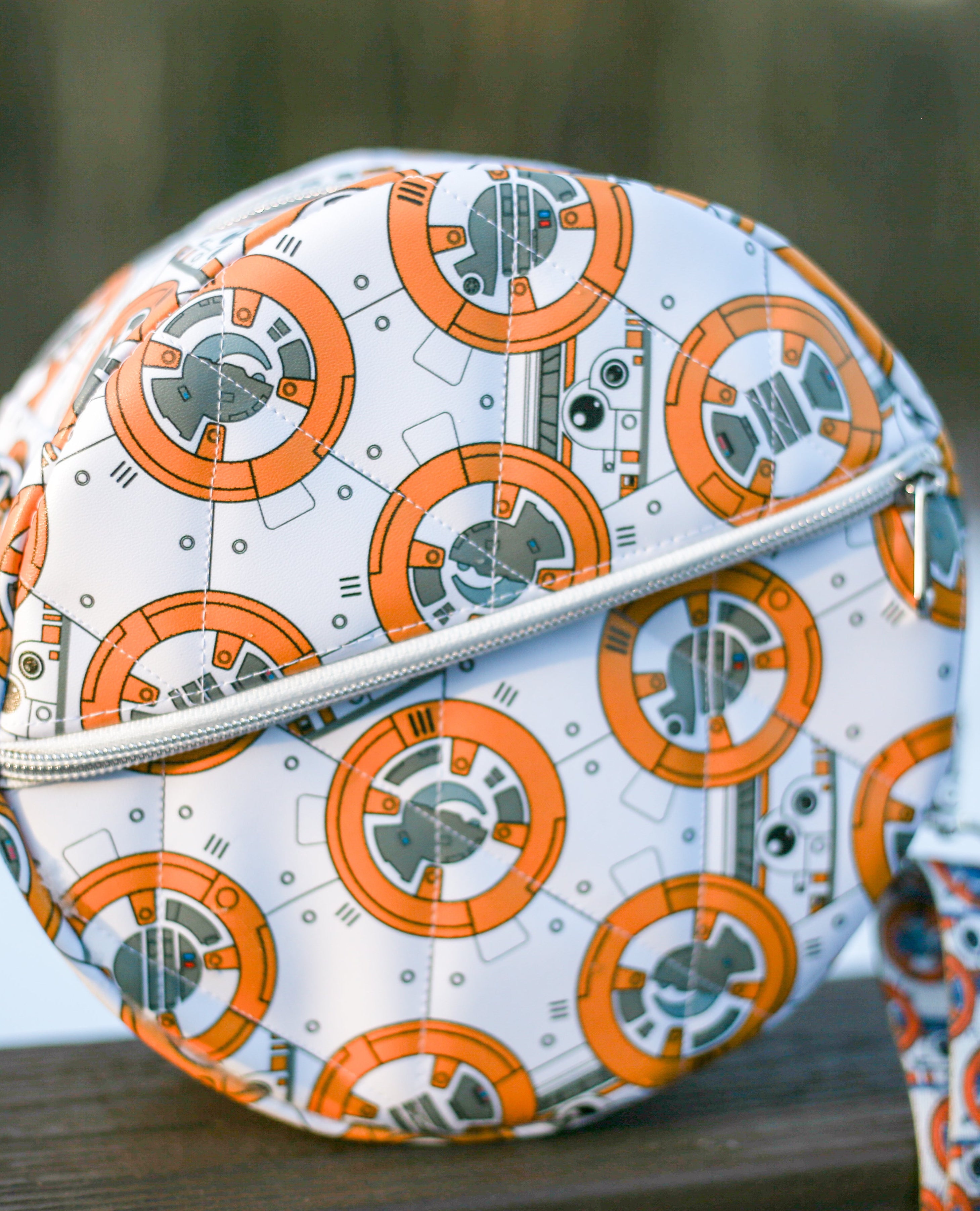 Round purse pattern with BB-8 design on a wooden surface with a blurred natural background. Front zip pocket.